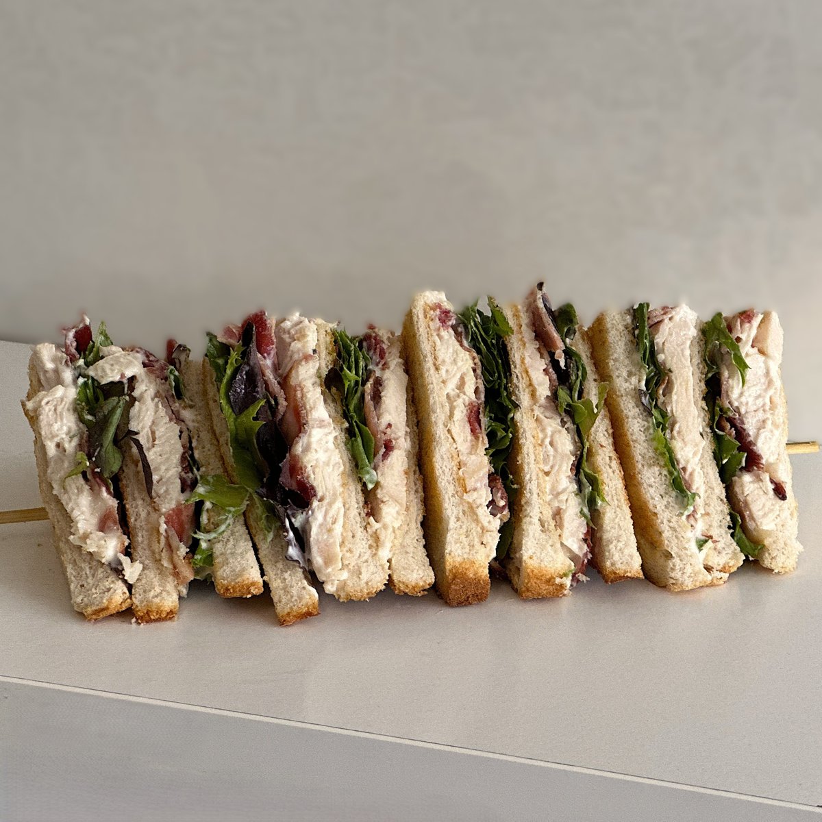 Club sandwiches stacked with roast chicken, bacon and salad leaves, cut into triangles